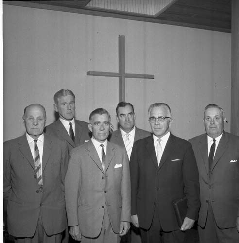 Sex herrar i mörka kostymer och slips står uppställda framför ett kors.
Nr 2 från vänster Sven Rickardsson, nr 4 Erik Olofsson, nr 5 pastor Robert Svensson.