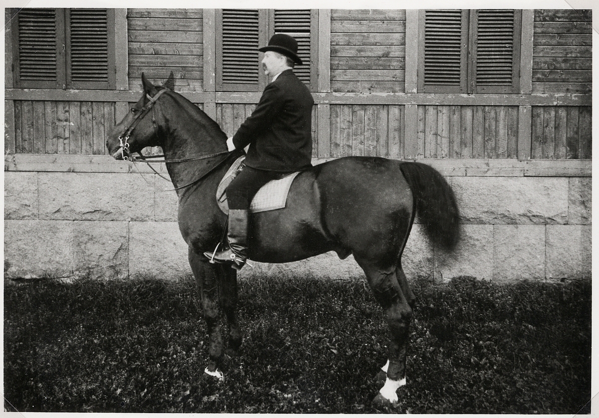 En medelålders man i kubb och kavaj sitter till häst, någonstans i Växjö, ca 1900. 
Fanjunkare m.m. Ludvig Nordström. Direktör i Växjö ridhusbolag.