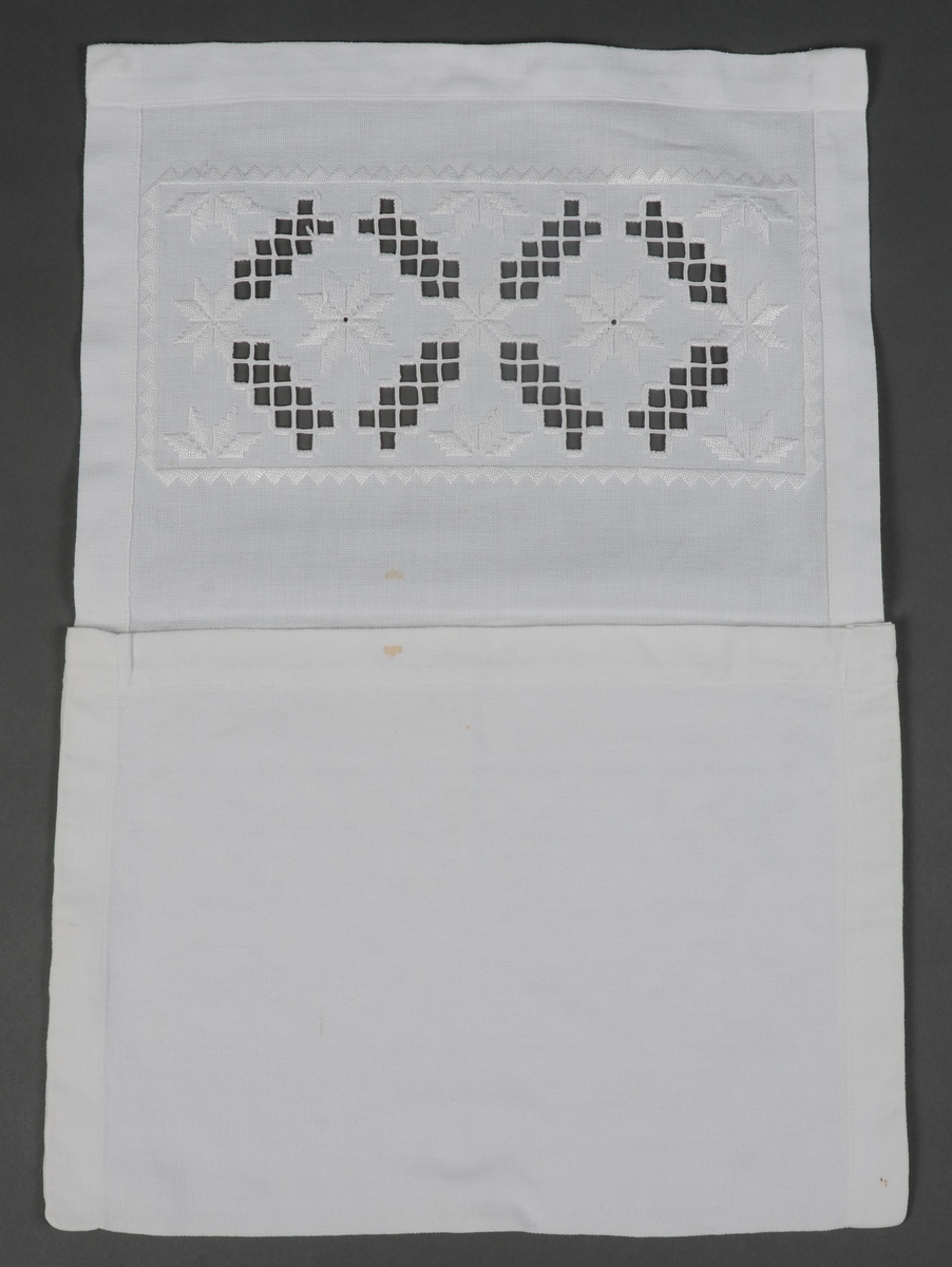 En tøymappe sydd av hvitt bomullsstoff dekorert med hardangerbroderi på lokket. Sidesømmene er sydd for hånd, resten med maskin.