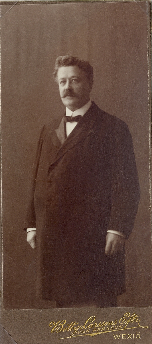 En äldre man i bonjour, stärkkrage och fluga.
Knäbild, halvprofil. Ateljéfoto, ca 1915.