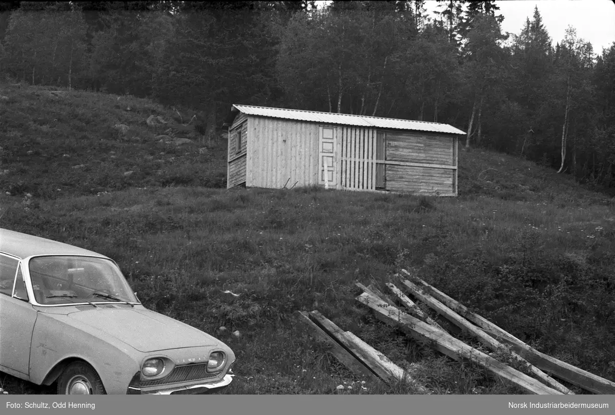 En bil, plank og et skur ved Krossobanens Øvre stasjon eller Gvepseborg. Bilen mangler registreringsskilt foran.