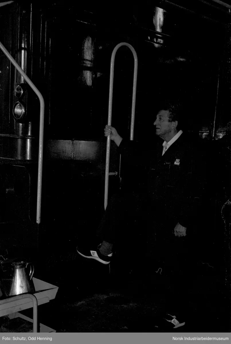Mann ved Henschel diesel-lokomotiv, inne i lokomotivstallen.