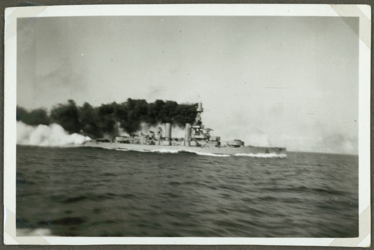 Bilden visar pansarskeppet Drottnings Victoria till sjöss. Svart rök bolmar ur skorstenen och kanonerna i bak har precist avlossats.