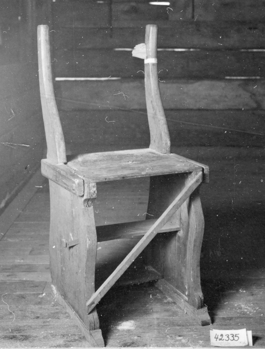Trappstol målad i gulgrå färg ,närmast kvadratisk sits,bakåtsvängd rygg i s-form. De 2 horisontella tvärslåar i ryggen saknas, gånjärn saknas. Stolen lagad med järnbult, under sitsen är trappstegen placerade då stolen är hopfälld.