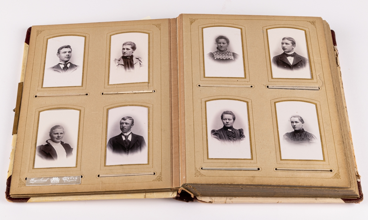Rött fotoalbum med metallspänne, textil, med pärm av lackat papper med motiv. Innehållande 57 visitkort. Många foton sakna. Porträtt över personer från Gästrikland.