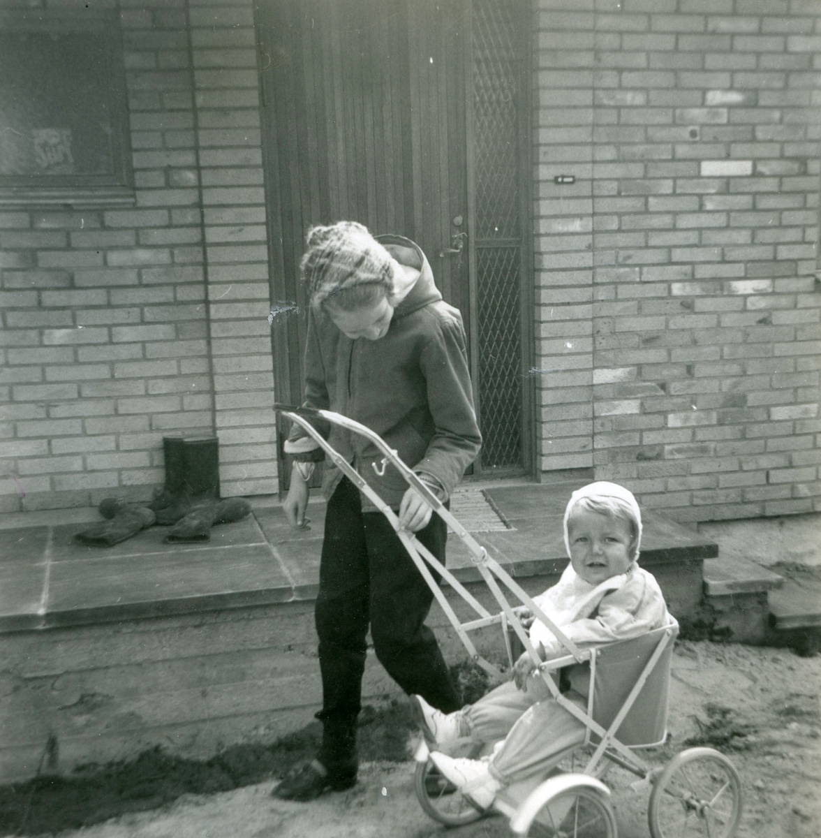 Kusin Ingela är på besök hos sin lille kusin Manne Ekman (född 1955) som sitter i en sulky utanför Villa Maribo (Streteredsvägen 29) våren 1957.