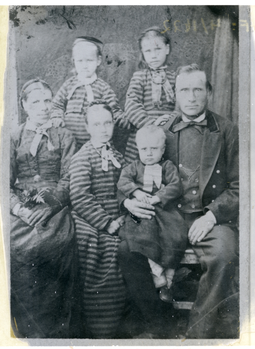 Familieportrett av ein mann og ei kvinne saman med fire barn. Dei yngste jentene er alle kledd i stripetet kjolar.
