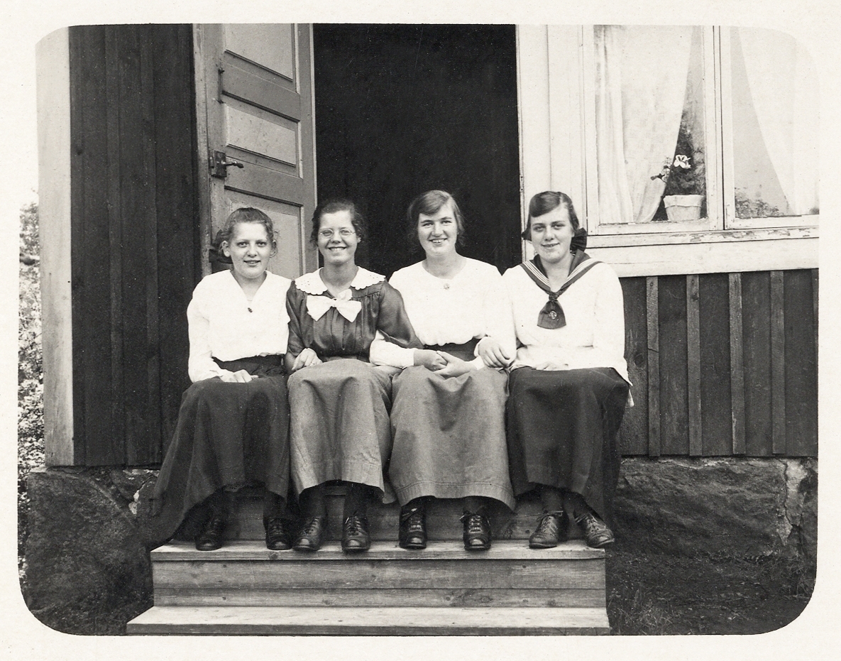 Fyra glada unga kvinnor sitter på en farstutrappa, ca 1920.