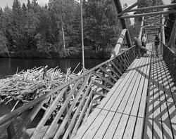 Tømmerhauger på motstrøms side av Klokkerfossbrua over Glomm