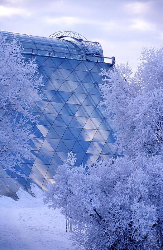 Vinterbilde av Hamardomen; rimede trær omkranser glassbygget som gjengir mange ulike blåtoner.