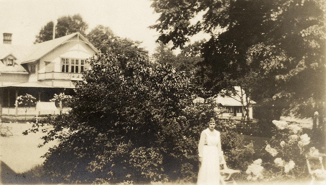 Evedal, Växjö, ca 1920. En kvinna i klänning och förkläde står i förgrunden, med restaurangen bakom sig.