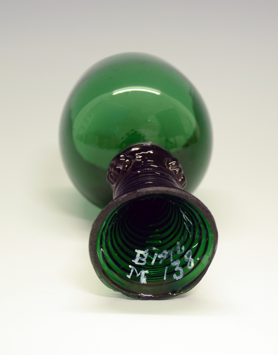 Vinglass Fra protokollen: Grønt kvitvinsglas, med staup i baae endar (jfr. bugge). Glaset kuppellaga, foten lurforma, runda med ein krans av 4 rosettar uppe. (R. Berge)