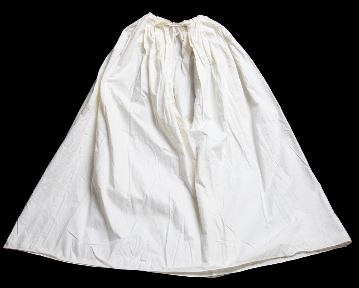 Underkjol att bära under dopklänning M 66048:1, vit dopklänning. Tillverkad av fin bomullslärft med veckad, insydd midja med påsydd linning och långt sprund mitt bak. Knyts med de i linningen fastsydda bomullsbanden.