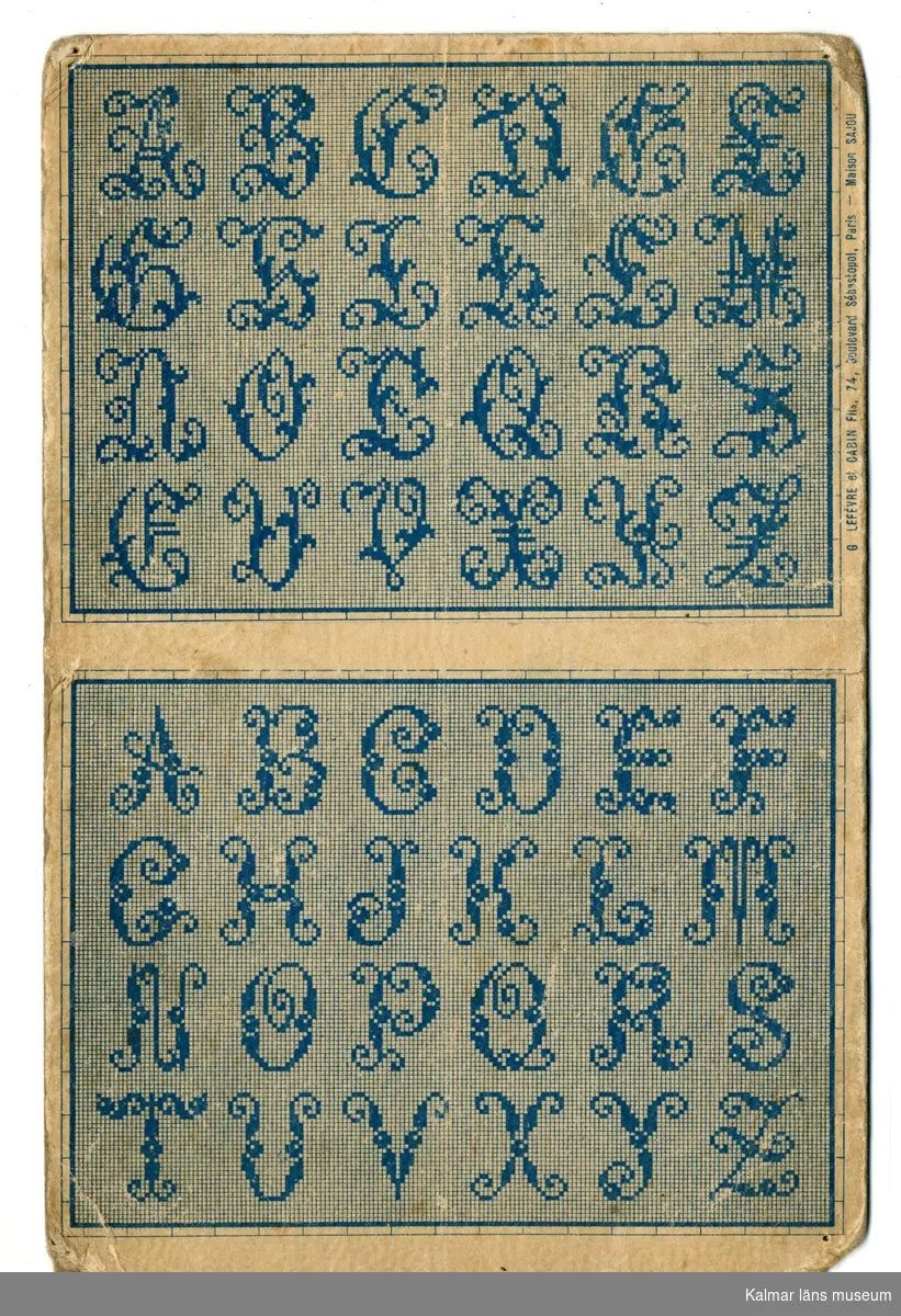 KLM 28509:377:31. Mönster, broderimönster. Av papper. Korsstygnsmönster föreställande alfabetet A-Z i blått. På baksidan finns en etikett med text.
