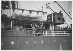 Vinkende personer ved relingen på et skip.