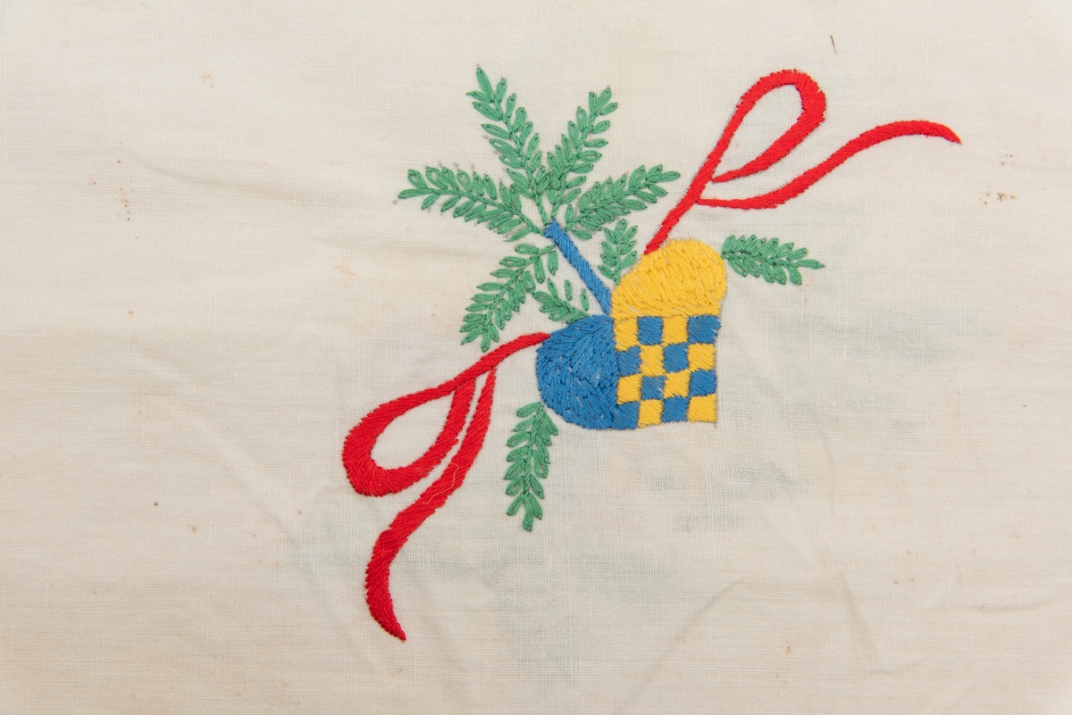Hvit duk med julemotiver brodert på. Det er brodert julekurver med fargene i det svenske flagget.