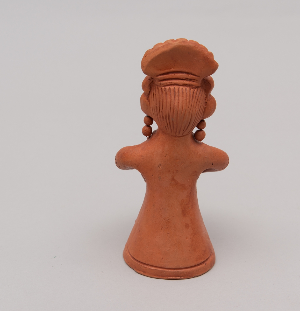 Rød keramikk kvinne-/gudinnefigur. Mulig bruksområde: telysholder.