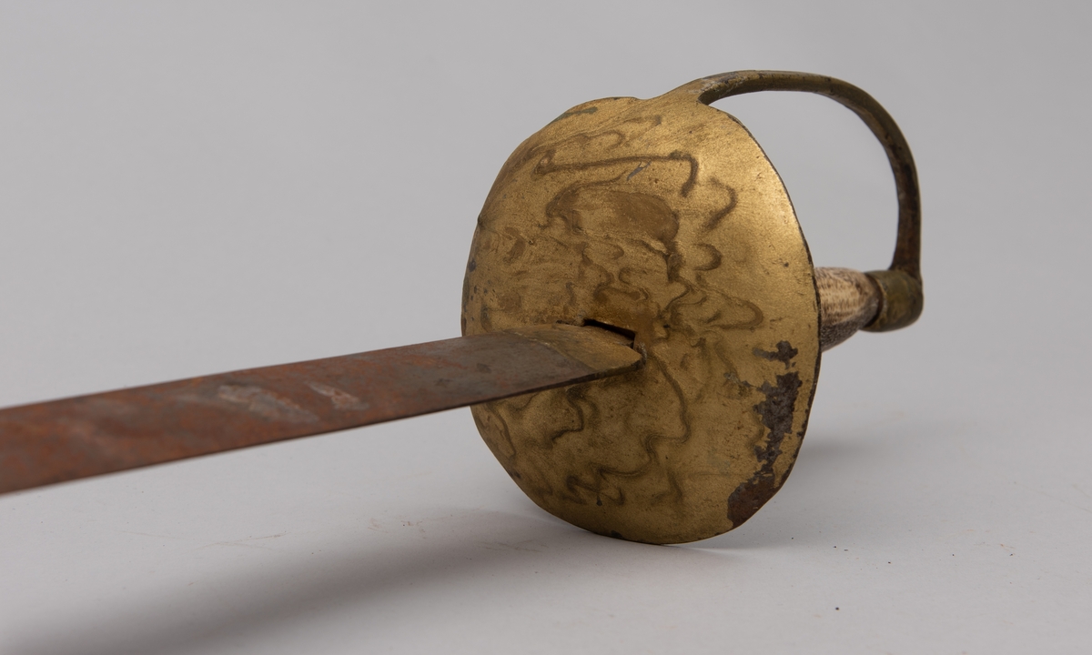 Hjemmesmidd blankvåpen brukt som rekvisitt. Parerplate og håndbøyle i stål, lakkert i gull.