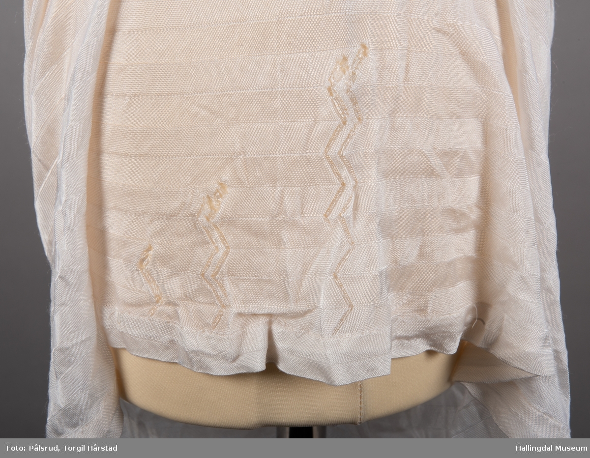 Hvitstripet underkjole i silke/bomull. Påsydde hvite blondekanter øverst i linning. Formsydd.