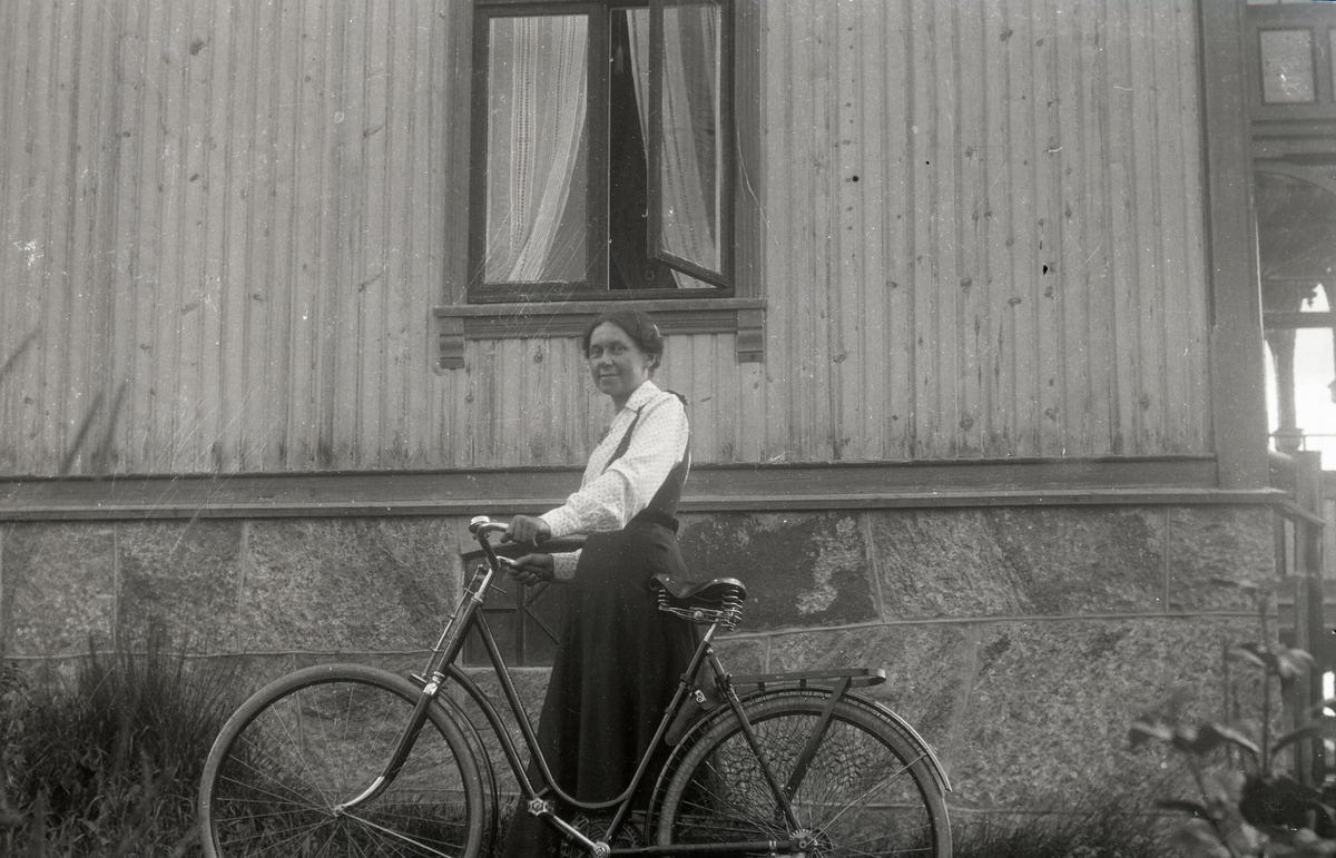 Kvinne med sykkel på utsida av ei bustadhus