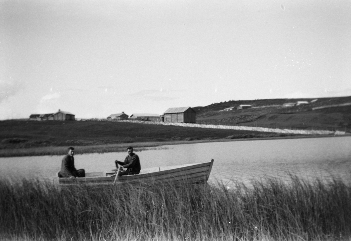Fjellvann og setre, robåt med to mann i forgrunnen, antakelig i Gausdal