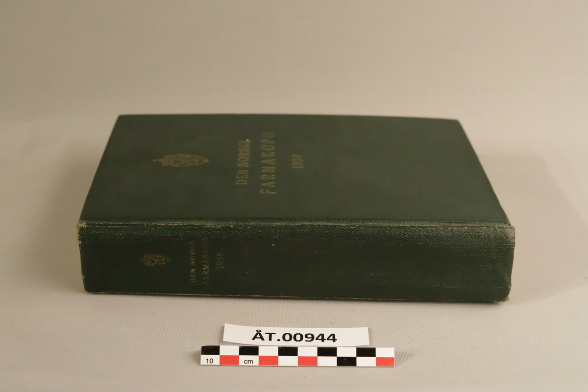 Mørkegrøn bok med gulldetaljer: Den norske farmakopø, 1939 (Pharmacopoes Norvegica Ed. V) Utgitt på offentlig opptak. I kommisjon hos H.Aschehoug & Co, Oslo 1939