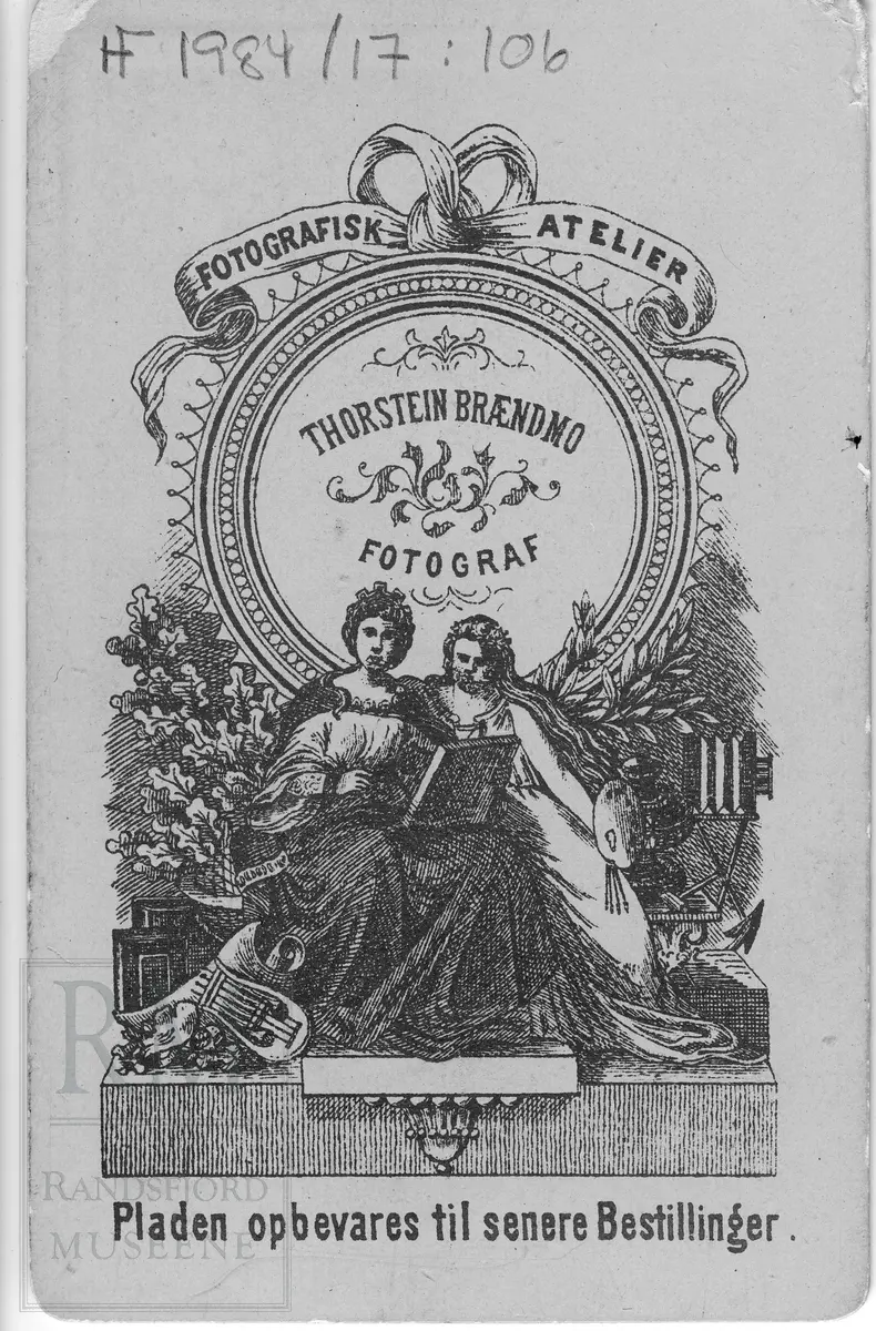 Brystbilde av ung kvinne i mørk kjole og hvit bred sløyfe i halsen festet med en stor nål.