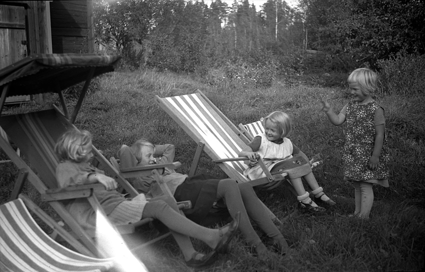 Fyra barn leker i gröngräset utanför hus. Västerås.