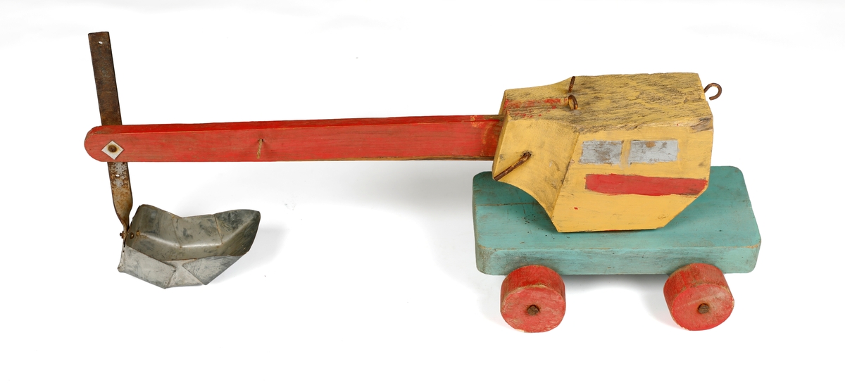 Gravemaskin, leketøy. Med hjul, kranen og skuffen kan beveges. Malt i rødt, turkis, gul og sølv.