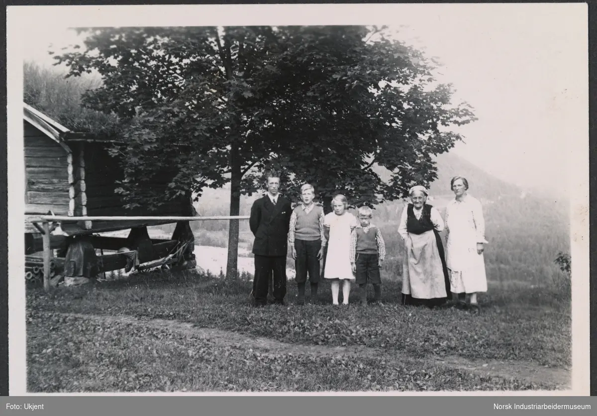 Familien Dahle, med spelemann Gunnar Dahle. Laftet stabbur ved siden av familien.
