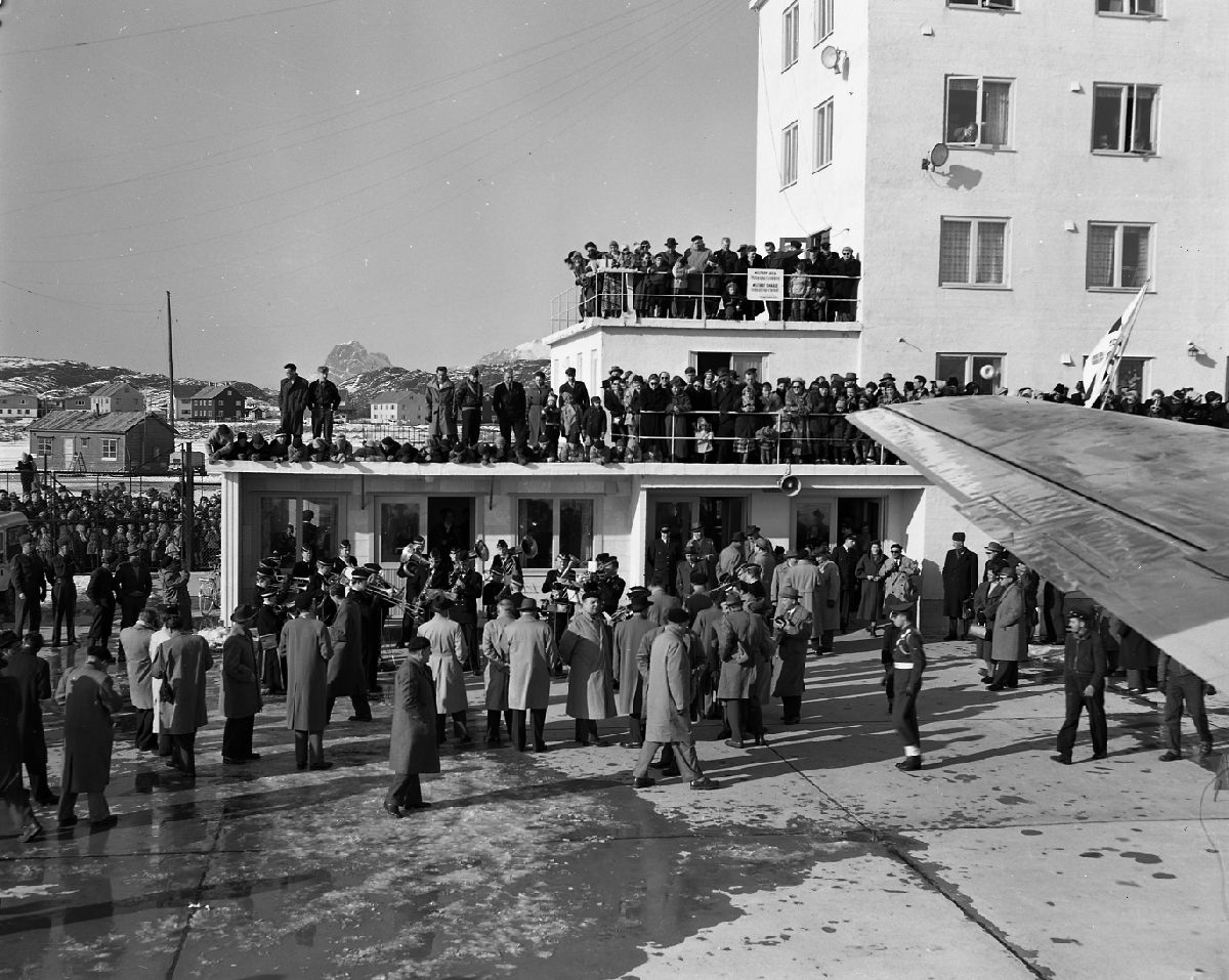 En stor menneskemengde og Bodø Guttemusikk var møtt opp på flyplassen da flyet med Wienerfilarmonikerne mellomlandet på tur fra Wien til Tokyo 6. april 1956.