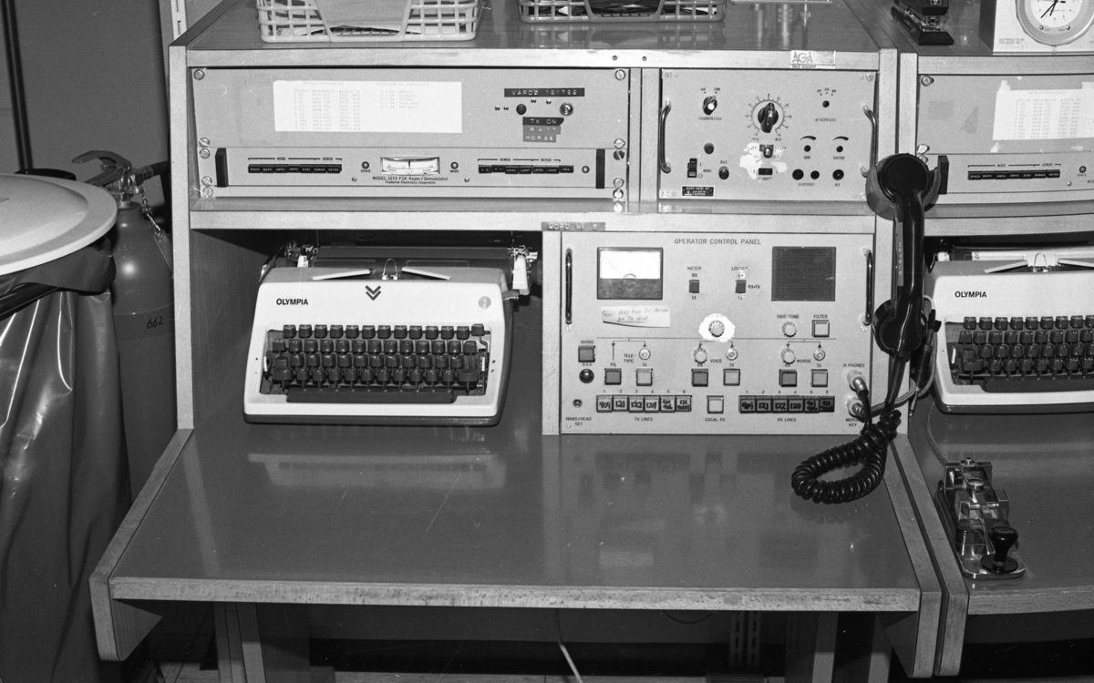 Sambandsutstyr brukt i forbindelse med radiokommunikasjon. Skrivemaskinen ble brukt til å dokumentere innkomne meldinger mottatt enten på telegrafi/morsemeldinger eller radiotale fra fly. Nederst til høyre ses en morsenøkkel.