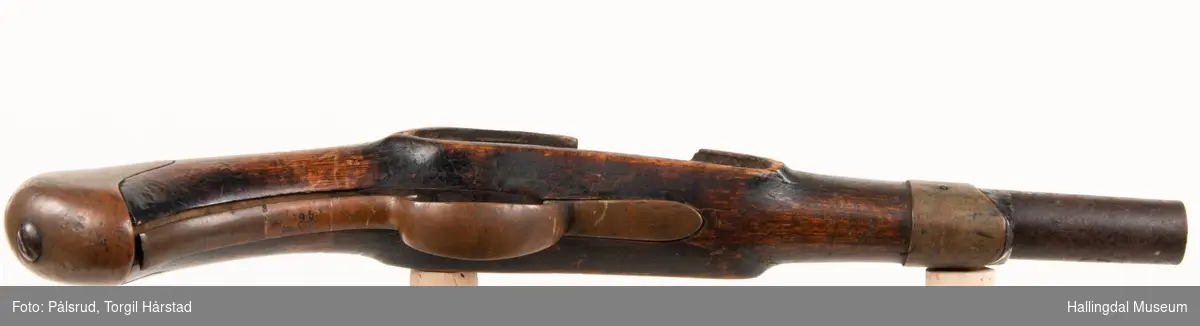 Kavaleripistol (rytterpistol), opprinnelig med flintlås. Mangler i dag låsen og ladestokk. Skjeftet er kuttet rett foran et messingbeslag. Messingbeslag på kolbe. Modell fra 1818, produsert på Kongsberg våpenfabrikk. Denne modellen hadde opprinnelig en løskolbe som kunne skiftes.
