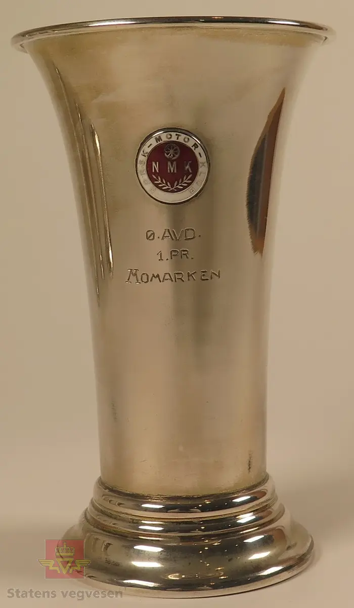 Pokal laget av sølv formet som et beger. Merking: NMK NORSK-MOTOR-KLUB Ø.AVD. 1.PR.