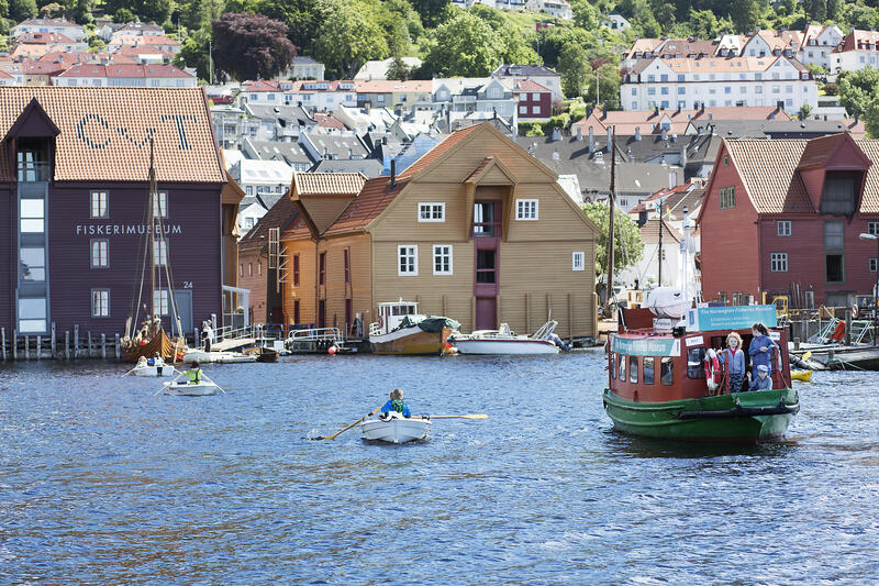 Her ser vi en aktiv havn, med flere robåter og Beffen som kommer inn til Norges Fiskerimuseum