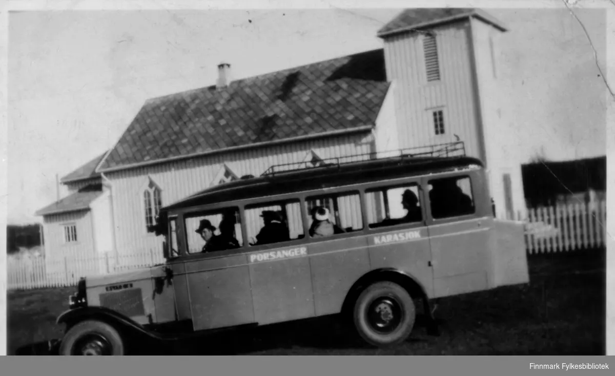 Bussen (Opel Blitz 1931) i ruta Porsanger-Karasjok. Kirke eller kapell i bakgrunn. 