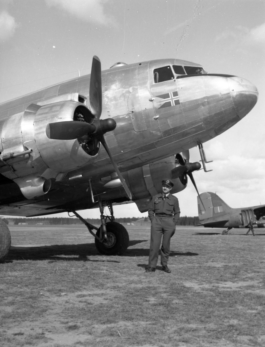 Et passasjerfly ved navn Douglas DC-3 Dakota på Fornebu. Pilot(?) står på bakken under nesen på flyet. 