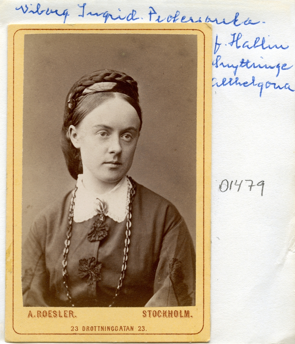 Porträtt av Ingrid Hallin, född i Fivelstad 1847. Dock uppvuxen i Västra Stenby, Allhelgona och Motala, innan hon 1872 gifte med bergsingenjören, sedermera professor, Johan Wiborgh. Paret var genom makens karriär bosatta i bland andra orterna Arboga och Sala innan de från 1884 var hemmavarande i Stockholm.