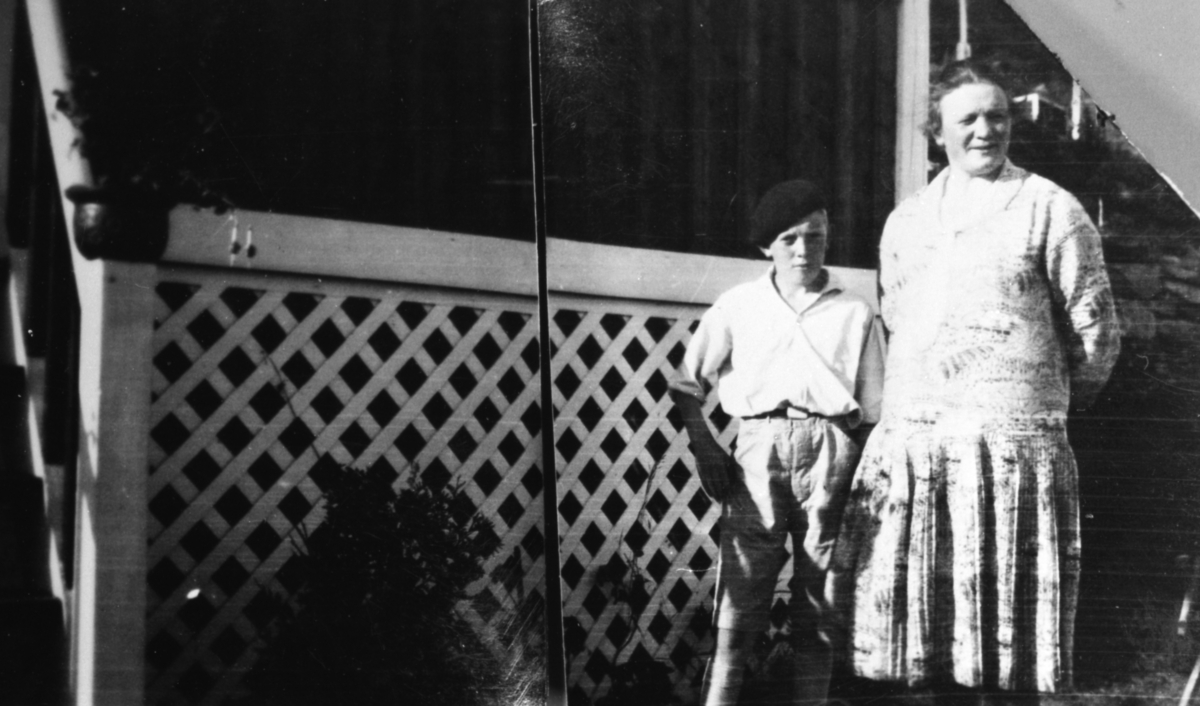 Portrett av ei kvinne og en gutt foran et hus.