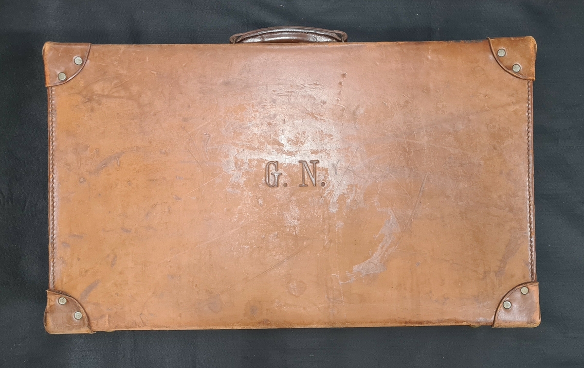 Resväska i brunt läder. På sidan finns på sidan G.N. , ägarens initialer.

Resväskan användes av järnhandlaren Georg Nyström (1874-1957), Vänersborg, vid handelsresor till Tyskland under 1920-talet. Han gjorde flera resor då man kunde inköpa varor för nästan ingenting i det krigshärjade Tyskland.