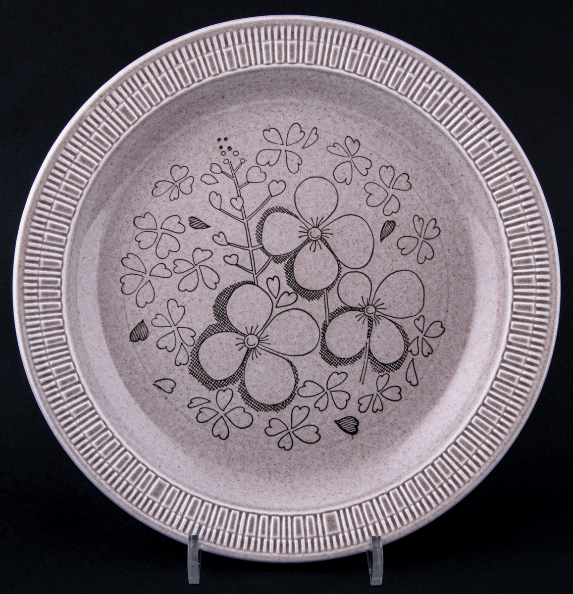 Flat tallrik från Gefle Porslin med provdekor, modell ER av Berit Ternell (skapad 1966). Ljusbrun glasyr med svarta blommor i stämpeltryck på tallrikens spegel.