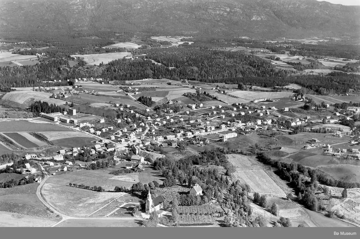 Flyfoto av Bøhaugen med kyrkjene og Bø sentrum frå vest. - Midt ...