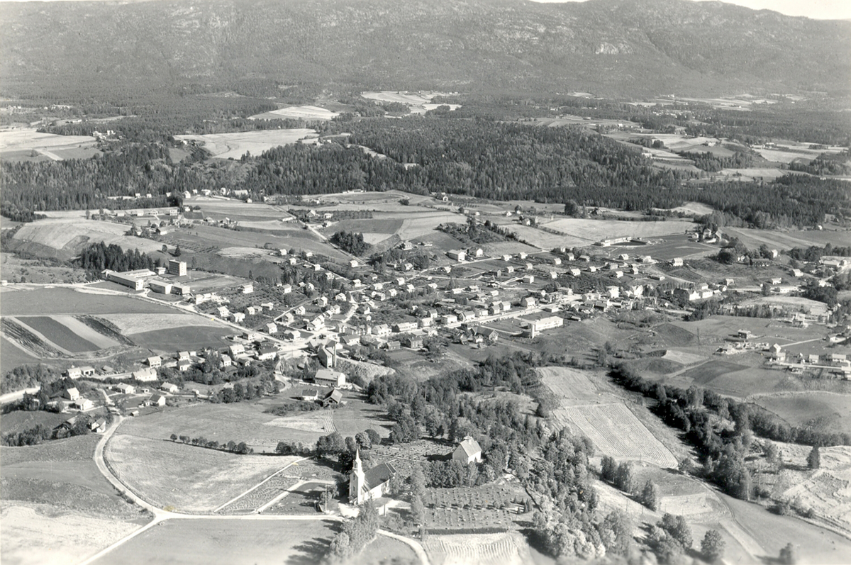 Flyfoto av Bøhaugen med kyrkjene og Bø sentrum frå vest.  Tatt 21. september 1963.