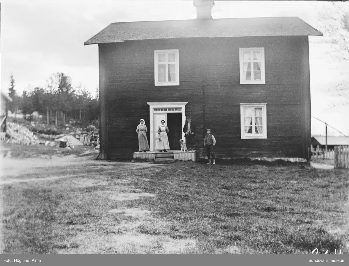 Fyra personer och en hund framför ett timrat boningshus på landsbygden i Stöde.