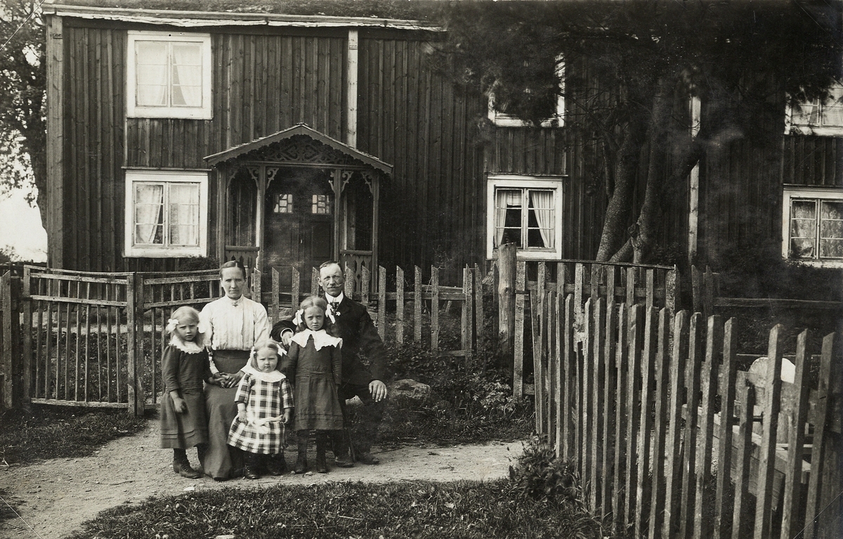 En familj är avfotograferade framför sitt hus, någonstans i länet.
Ca 1910.