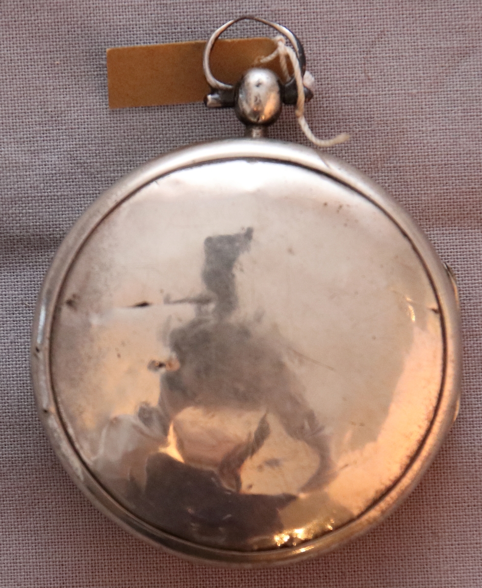 Större fickur av silver med dubbelboett. Uppdragning från urtavlan. På boettens insida står. W.4 = 1851. c.c.a. På klockverkets baksida ”Brequet” och ”A Fil(?)”.