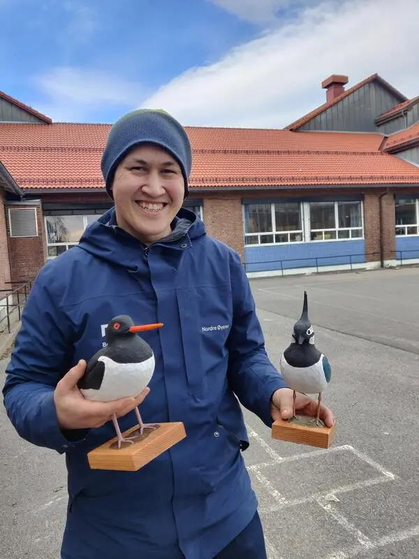 Foto av naturveileder i en skolegård og holder to trefugler