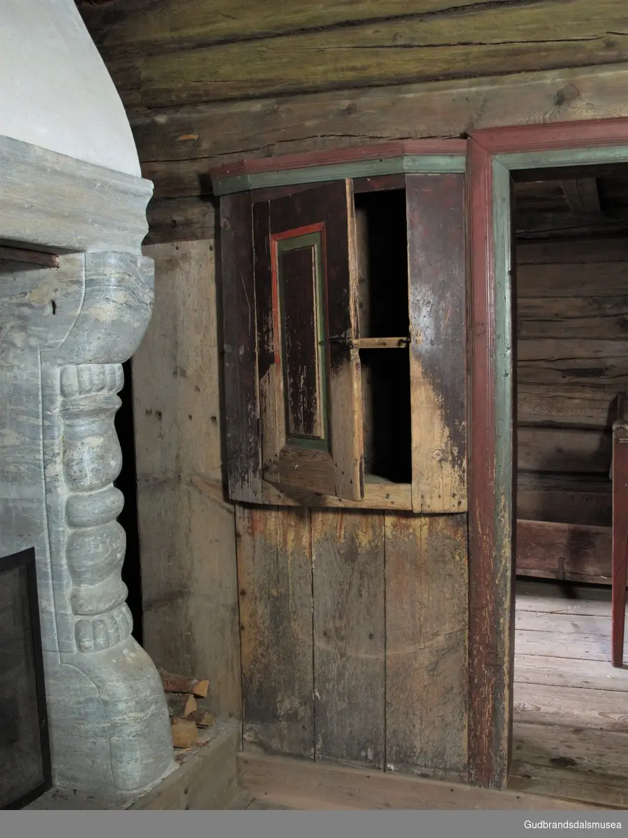 Lite innebygd skap i stue fra 1700-tallet. Skaprom delt av hylle på midten. Dør og skapramme er tappet og med treplugger gjennomtappene. Malt i brun, rød og grønn, en fargebruk som ble vanlig fra slutten på 1700-tallet.