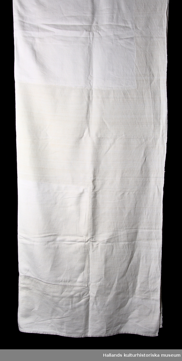 Lakan - alternativt sängöverkast - av grovt vitfärgat linne. Överkastet har lagningar bestående av två rektangulära lappningar.