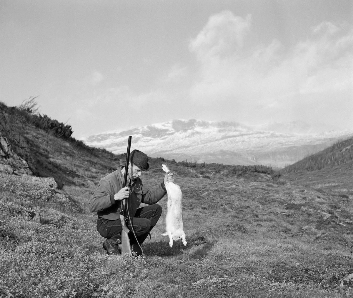 Jeger med en hare han har skutt under harejakt i Jotunheimen. Bildet er tatt i oktober 1961.